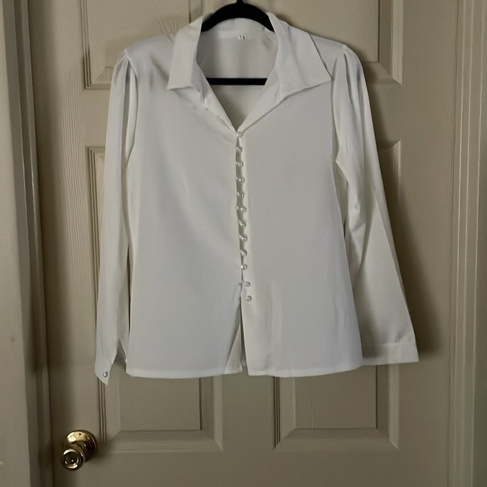 Polyester white blouse 25.5” long, buttons down the front and the cuffs are NWOT